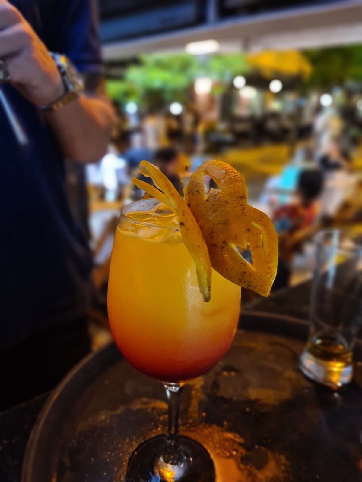 Drink em tons de pôr do sol com decoração cítrica